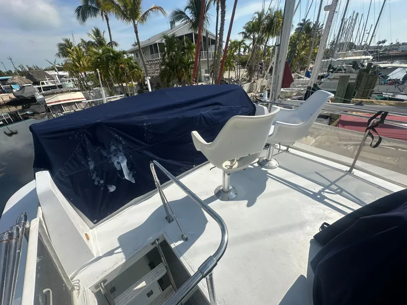 Slide: The Image of 1974 Bertram 42 Motor Yacht deck with chairs, marina view, and palm trees in the background. - 21
