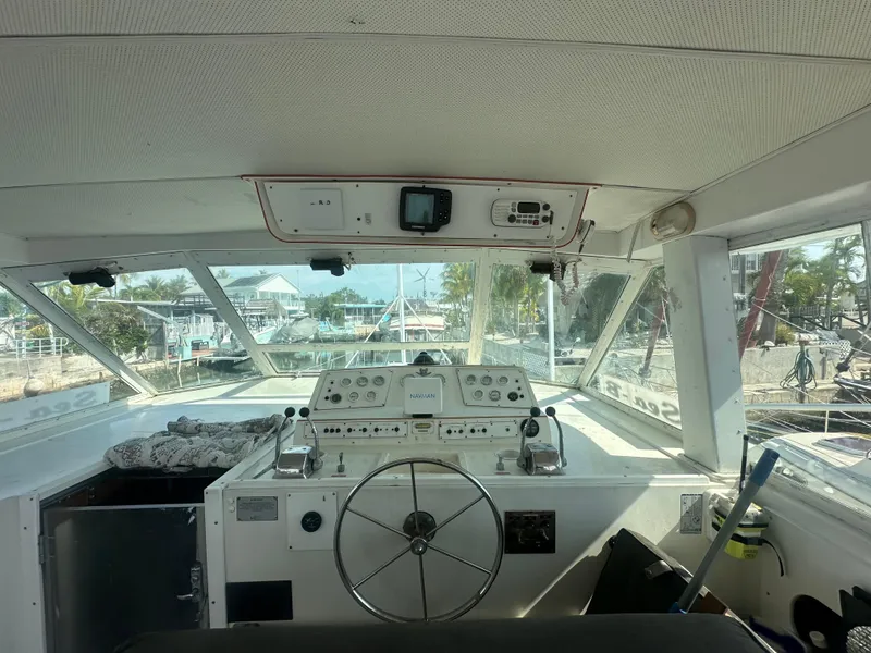 Slide: The Image of 1974 Bertram 42 Motor Yacht helm with steering wheel and navigation controls, dockside view. - 23