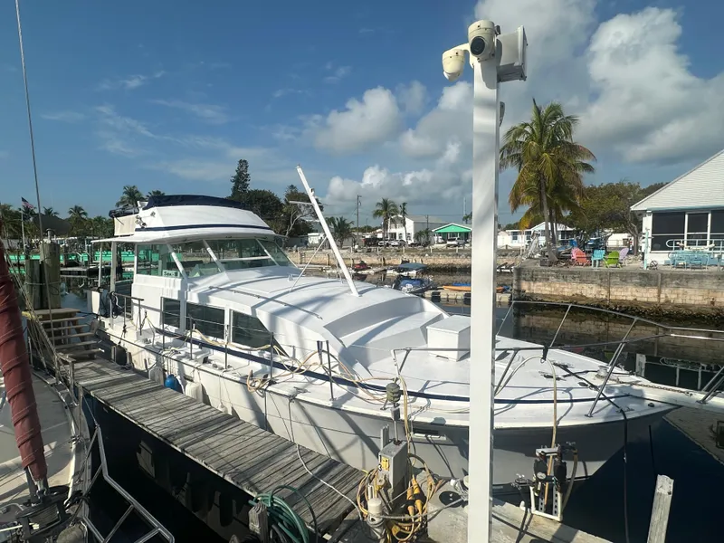 Slide: The Image of 1974 Bertram 42 Motor Yacht docked at a marina under a partly cloudy sky. - 3