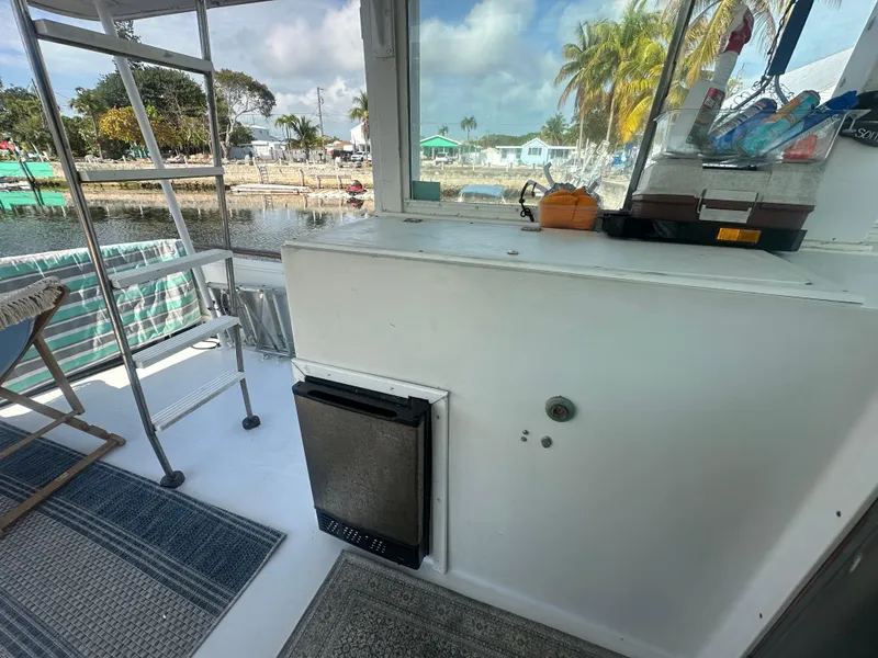 Slide: The Image of 1974 Bertram 42 Motor Yacht interior with kitchenette, outdoor view, and tropical setting. - 31