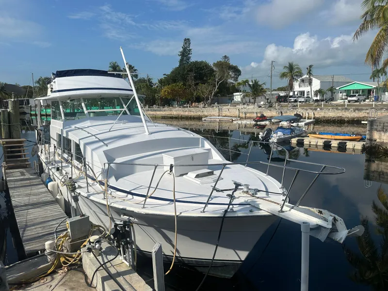 Slide: The Image of 1974 Bertram 42 Motor Yacht docked in a marina, surrounded by calm water and palm trees. - 4
