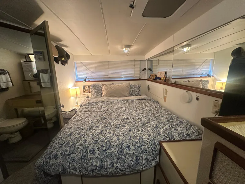 Slide: The Image of 1974 Bertram 42 Motor Yacht bedroom with patterned bedding, mirrors, and cozy lighting. - 45
