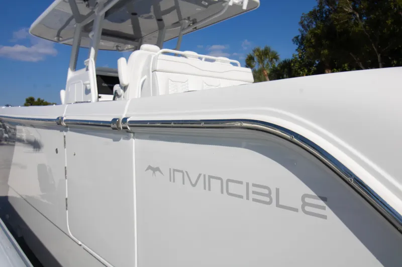 Slide: The Image of 2026 Invincible 36 Catamaran, sleek white design, side view with logo, clear blue sky. - 38