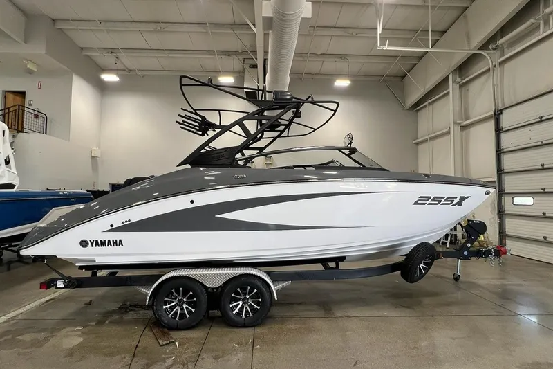 The Image of 2025 Yamaha Boats 255XE in showroom, sleek design, on trailer, side view. - 0