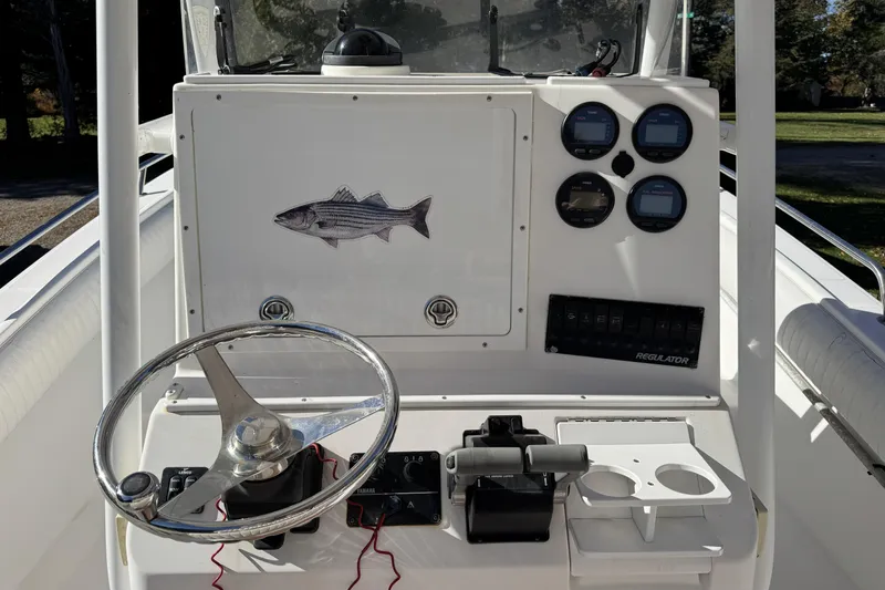 Slide: The Image of 2004 Regulator 24 Forward Seating boat dashboard with steering wheel and gauges. - 16