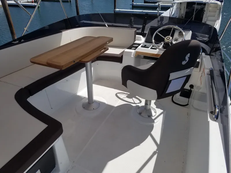 Slide: The Image of 2019 Beneteau Swift Trawler 35 cockpit with steering wheel, seating, and wooden table. - 21