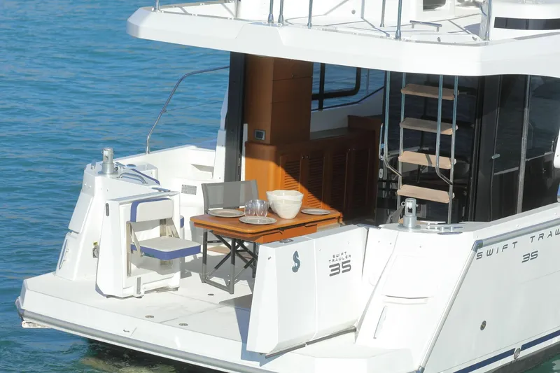 Slide: The Image of 2019 Beneteau Swift Trawler 35, rear deck view with seating and table setup. - 3