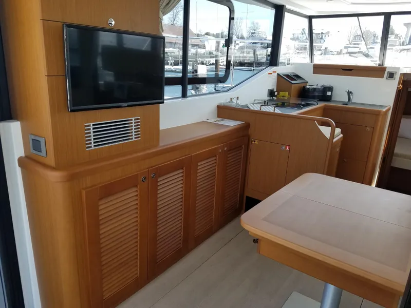 Slide: The Image of 2019 Beneteau Swift Trawler 35 interior with wood cabinetry, TV, and kitchen area. - 31