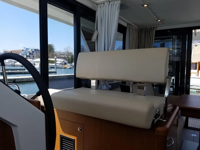 Slide: The Image of 2019 Beneteau Swift Trawler 35 interior with beige seating and marina view. - 35