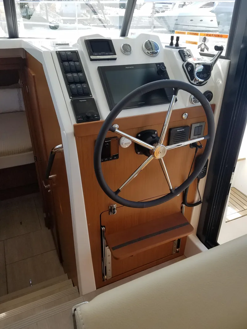 Slide: The Image of 2019 Beneteau Swift Trawler 35 helm with modern navigation controls and wooden accents. - 37