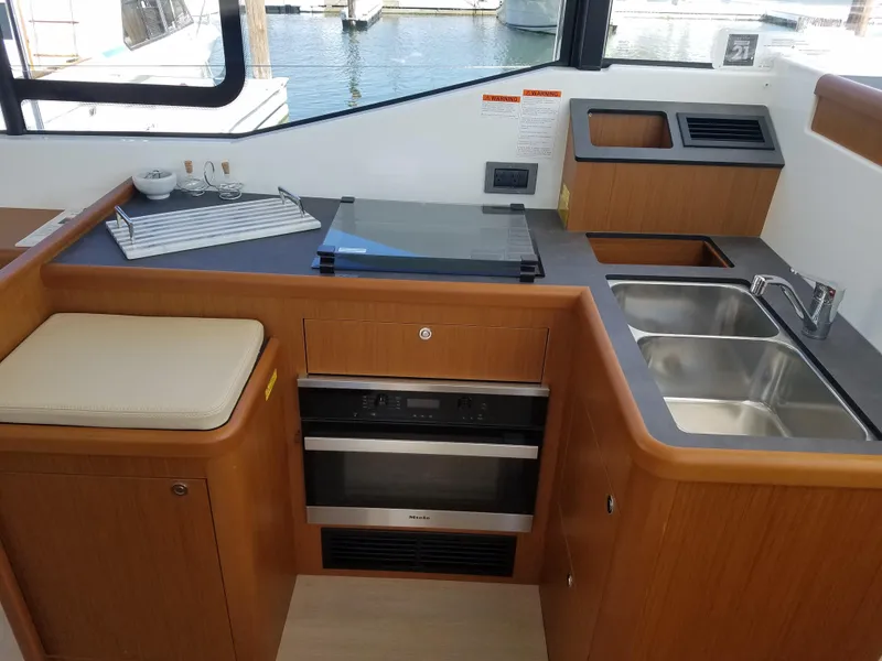 Slide: The Image of 2019 Beneteau Swift Trawler 35 kitchen with stove, sink, and wooden cabinetry. - 43