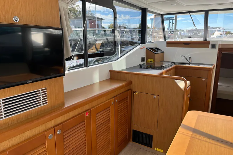 Slide: The Image of 2019 Beneteau Swift Trawler 35 interior with kitchen and TV, featuring wood cabinetry. - 44