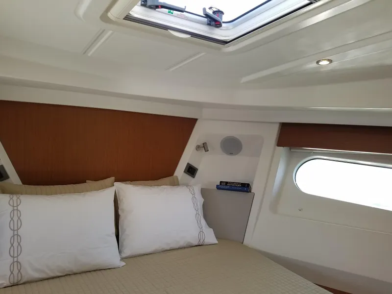 Slide: The Image of 2019 Beneteau Swift Trawler 35 cabin interior with bed, pillows, and window. - 49
