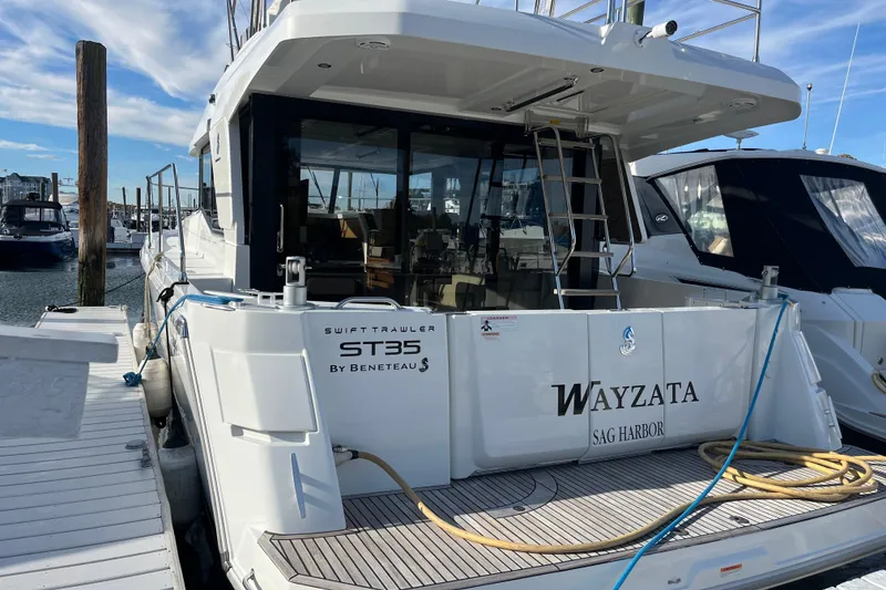 Slide: The Image of 2019 Beneteau Swift Trawler 35 docked at marina, rear view with open deck. - 6