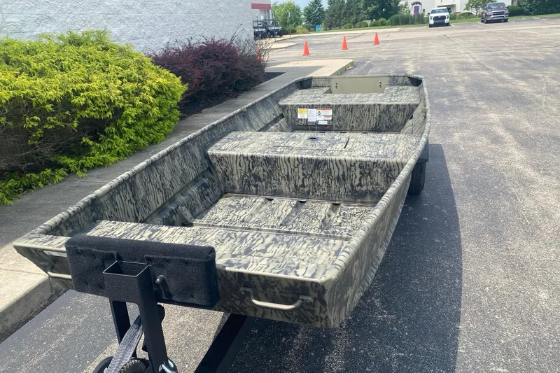 Slide: The Image of 2026 Tracker Grizzly 15 Jon boat with camouflage design on a trailer in a parking lot. - 3