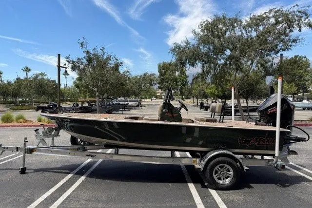 Slide: The Image of 2026 Mako 18 Pro Skiff Backwater Edition on trailer in sunny parking lot. - 2