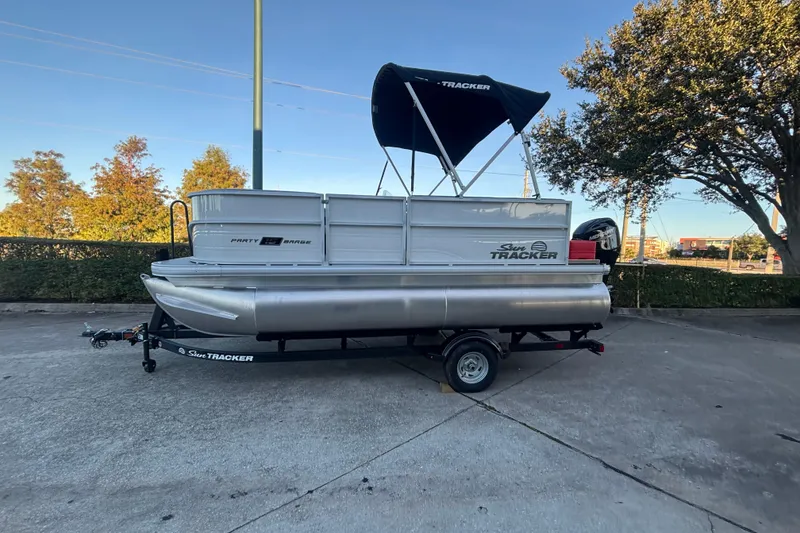 The Image of 2026 Sun Tracker Party Barge 16 DLX pontoon boat on trailer, parked outdoors. - 0
