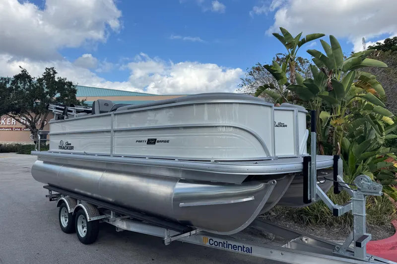 The Image of 2026 Sun Tracker Party Barge 22 XP3 pontoon boat on trailer, parked outdoors. - 0