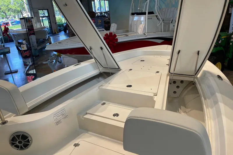 Slide: The Image of 2026 Mako 24 APEX boat interior with open storage compartments in showroom. - 2