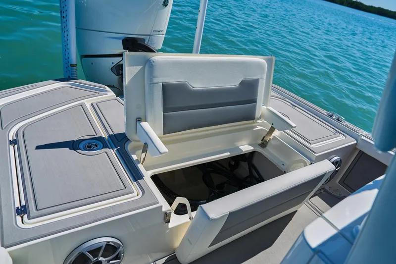 Slide: The Image of 2026 Mako 24 APEX boat with open storage compartment on a sunny day. - 83