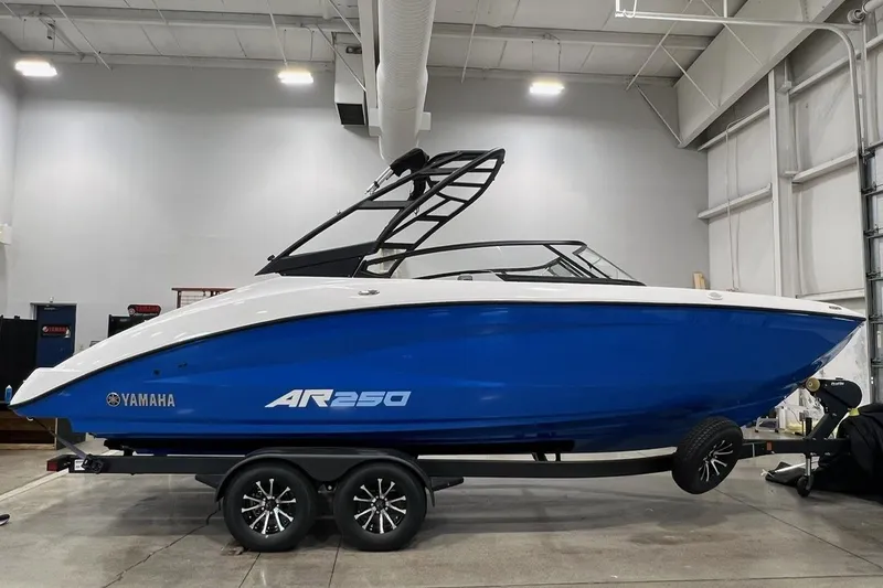 The Image of 2025 Yamaha AR250 boat in a showroom, featuring a sleek blue and white design. - 0