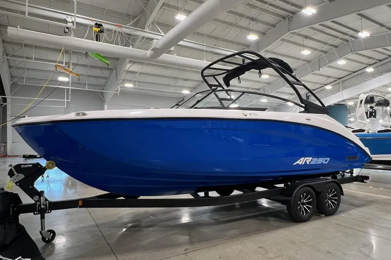 Slide: The Image of 2025 Yamaha Boats AR250 in a showroom, featuring sleek blue design and modern architecture. - 2