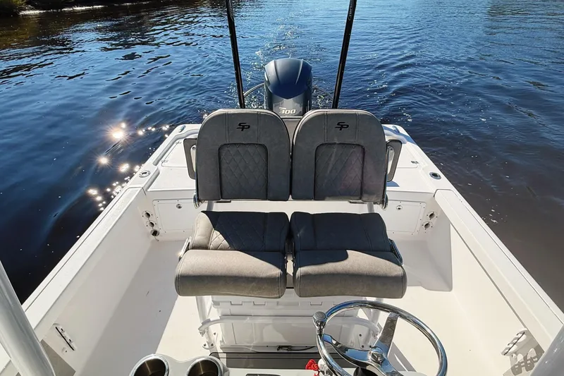 Slide: The Image of 2021 Sea Pro 248 Bay boat interior with dual seats and steering wheel on water. - 14
