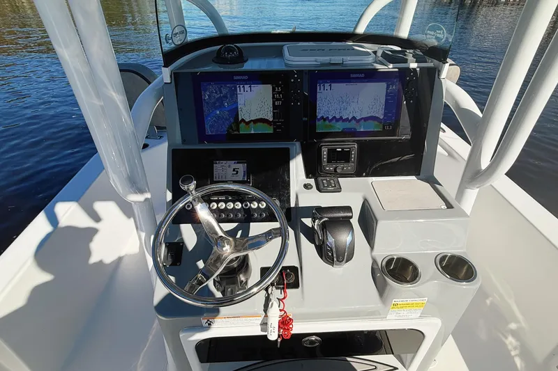 Slide: The Image of 2021 Sea Pro 248 Bay boat dashboard with steering wheel and navigation screens. - 7