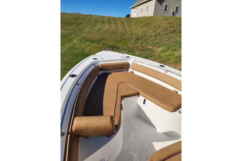 Slide: The Image of 2023 Sea Hunt Ultra 239 SE boat with tan seating, docked on grassy area. - 5