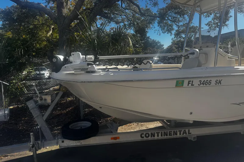 Slide: The Image of 2018 Carolina Skiff Ultra Series boat on trailer, parked outdoors with trees in background. - 11