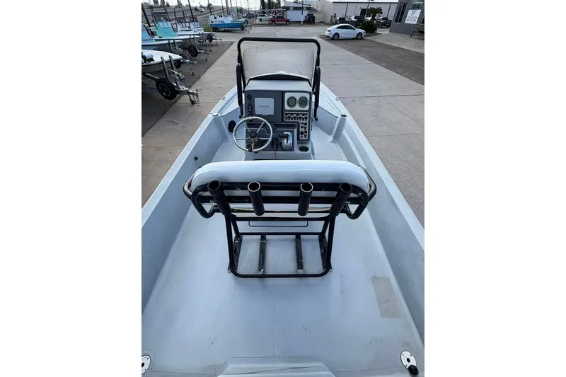 Slide: The Image of 2016 BLUEWAVE 2200 boat interior with steering console and seating, docked outdoors. - 4