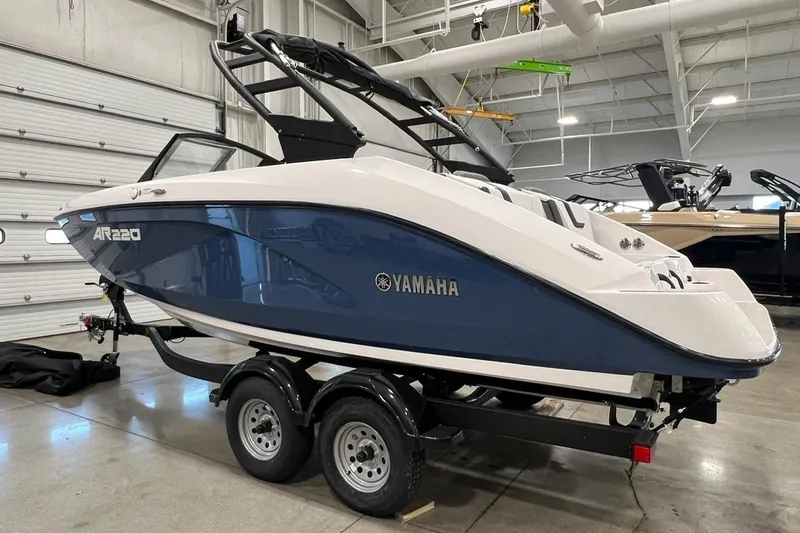 Slide: The Image of 2025 Yamaha Boats AR220 in showroom, blue and white design, on trailer. - 2