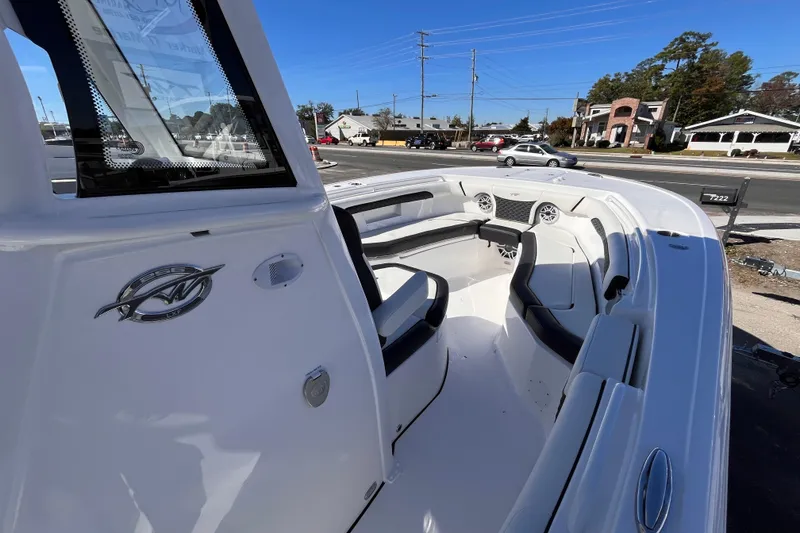 Slide: The Image of 2026 Tidewater 256 LXF boat interior with seating and dashboard, parked outdoors. - 12