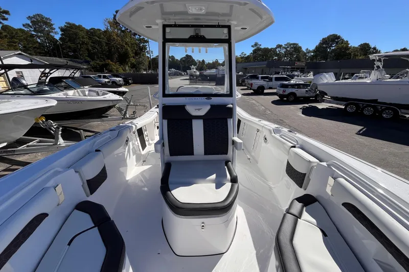Slide: The Image of 2026 Tidewater 256 LXF boat interior with seating, parked in a marina under clear blue sky. - 14