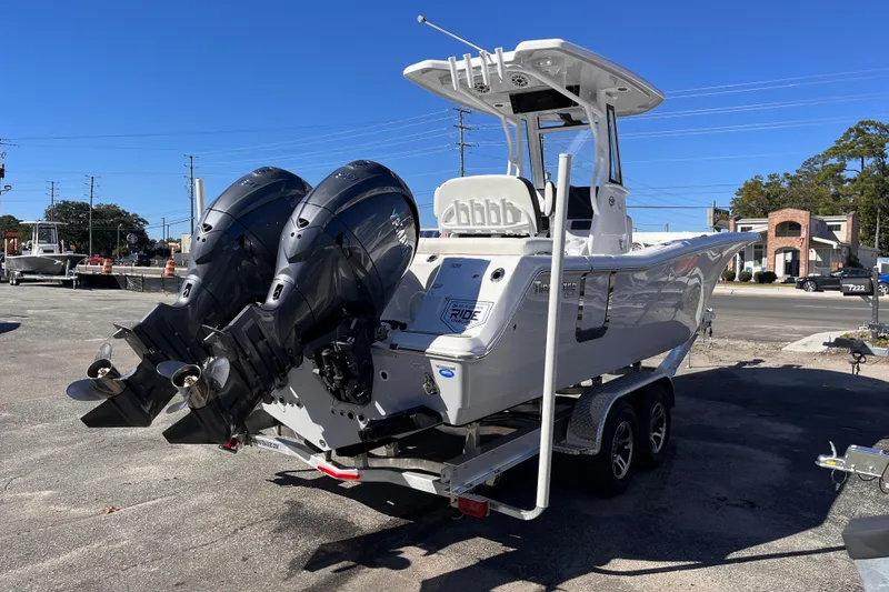 Slide: The Image of 2026 Tidewater 256 LXF boat with dual engines on a trailer, parked outdoors. - 5
