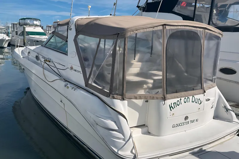 The Image of 1997 Sea Ray 330 Sundancer boat docked, featuring tan canopy and "Knot on Duty" text. - 1