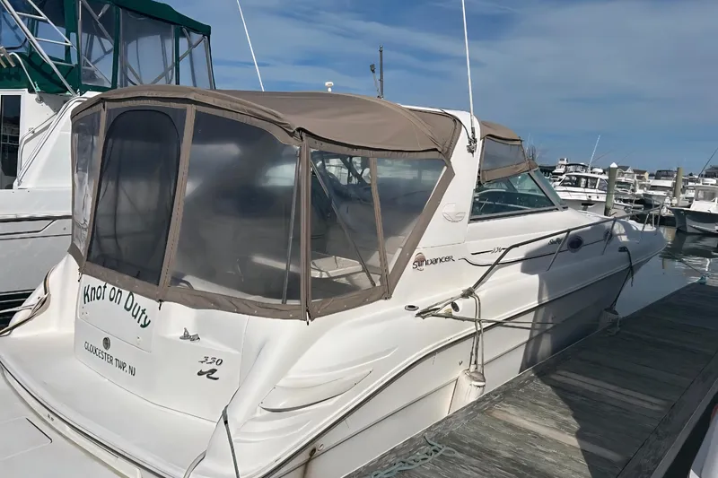 Slide: The Image of 1997 Sea Ray 330 Sundancer docked at marina, featuring tan canopy and sleek design. - 4