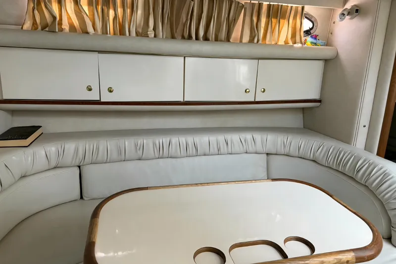 Slide: The Image of Interior of a 1997 Sea Ray 330 Sundancer with white seating and wooden table. - 9