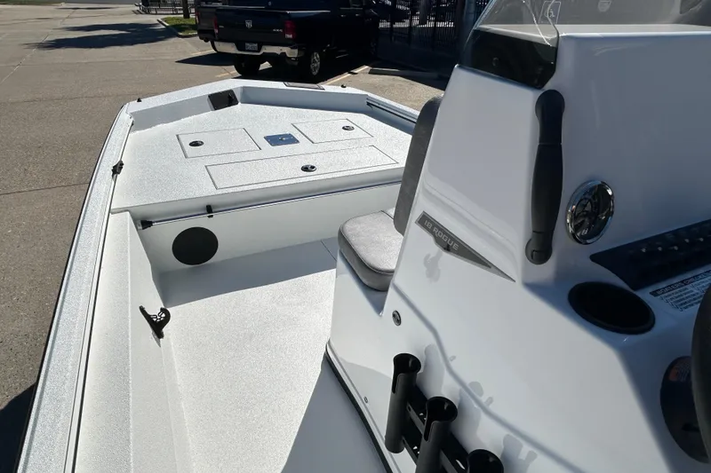 Slide: The Image of 2026 Avid 18 Rogue CC boat interior with console and seating, parked outdoors. - 11