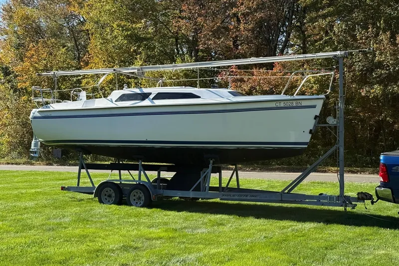 The Image of Catalina 250 MkII sailboat on trailer, parked on grass, surrounded by autumn trees. - 1