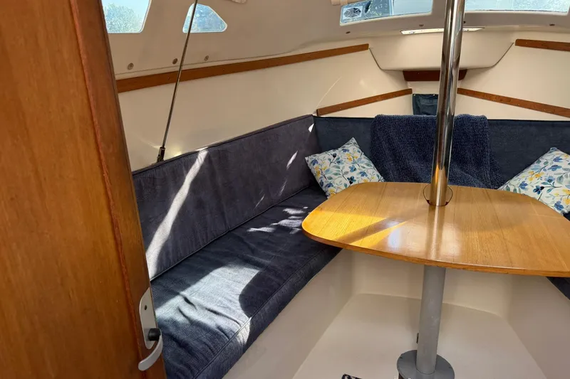 Slide: The Image of Cozy interior of a 2000 Catalina 250 MkII sailboat with cushioned seating and wooden table. - 17