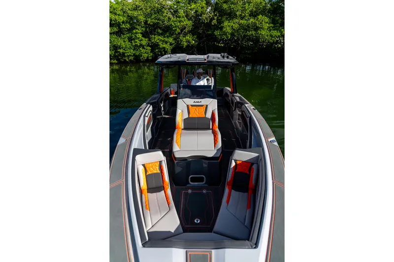 Slide: The Image of 2026 AMP 333 boat with modern seating, sleek design, and vibrant orange accents on a calm waterway. - 16