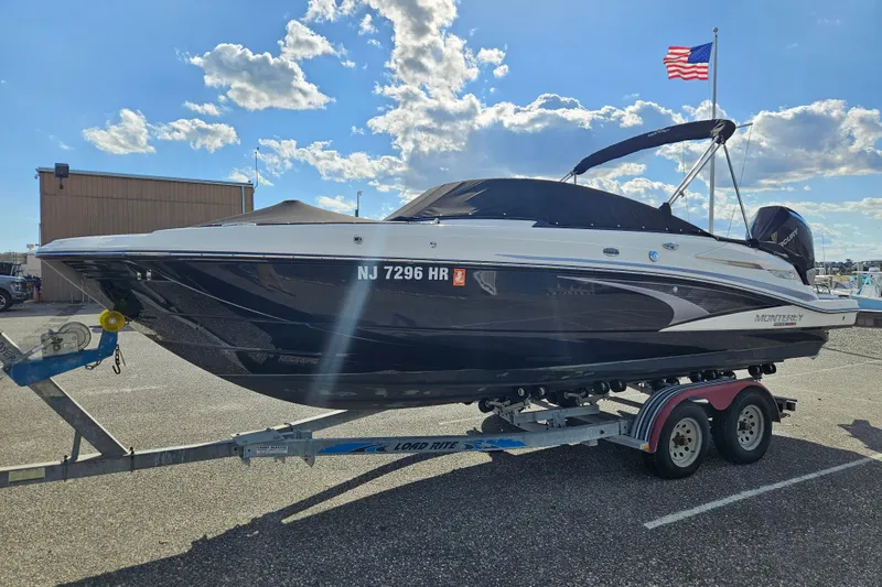 Slide: The Image of 2022 Monterey M-45 boat on trailer, parked under a clear blue sky with American flag. - 5