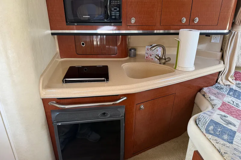 Slide: The Image of 2005 Sea Ray 290 Amberjack cabin kitchen with sink, microwave, and storage cabinets. - 16