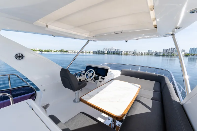 Slide: The Image of 2023 Azimut Fly 50 yacht flybridge with seating, table, and helm overlooking water. - 44