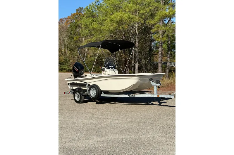 Slide: The Image of 2024 Mako Pro Skiff 15 CC boat with Mercury engine on trailer, parked outdoors. - 2