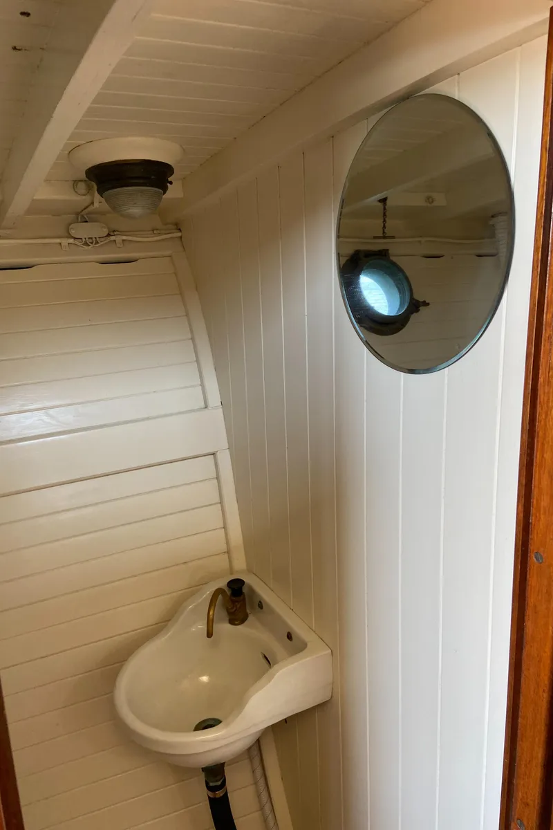 Slide: The Image of 1929 Classic Lobster Cruiser interior with white paneling, round window, and small sink. - 10