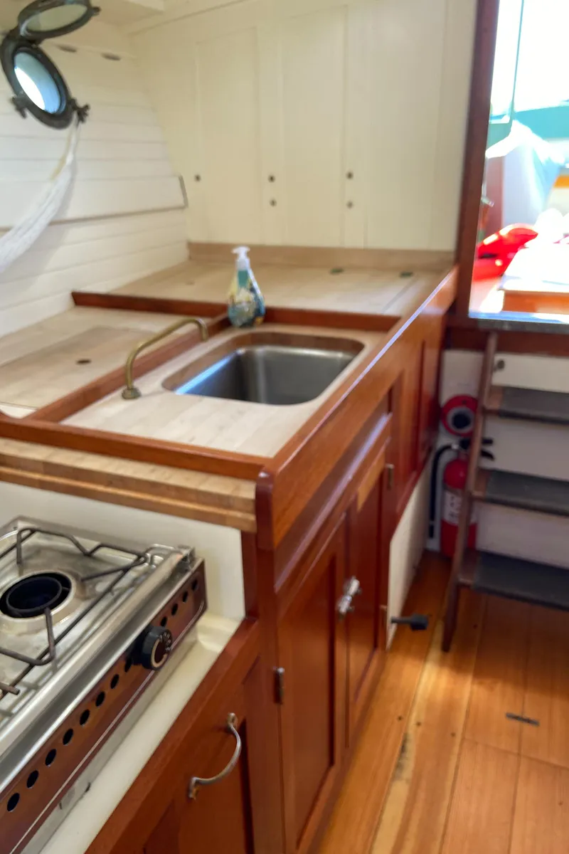 Slide: The Image of 1929 Classic Lobster Cruiser kitchen with wooden cabinets, sink, and stove. - 12