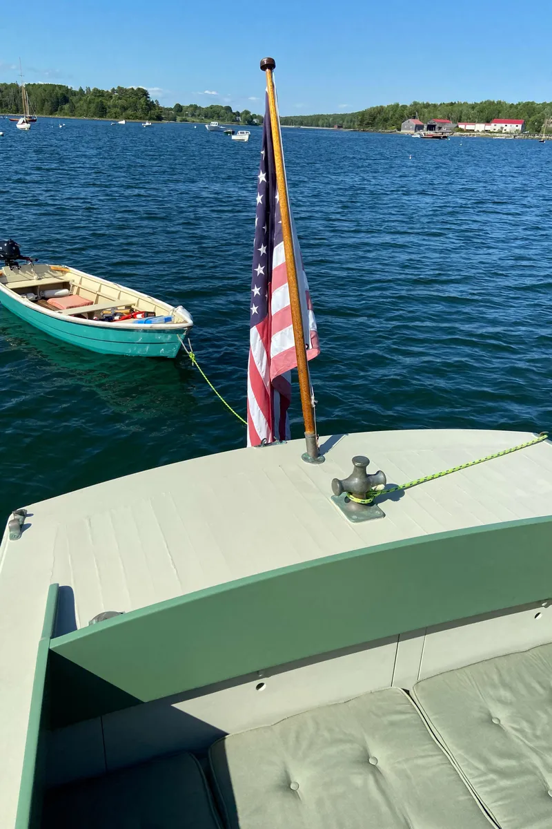 Slide: The Image of 1929 Classic Lobster Cruiser on serene lake with American flag and small boat nearby. - 15