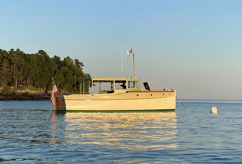 Slide: The Image of Classic 1929 Lobster Cruiser boat on calm water near a forested shoreline. - 3